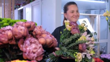 Çiçekçi kadın çiçek dükkanında müşteri ile büyük çiçek buket ve görüşmeler yapar.