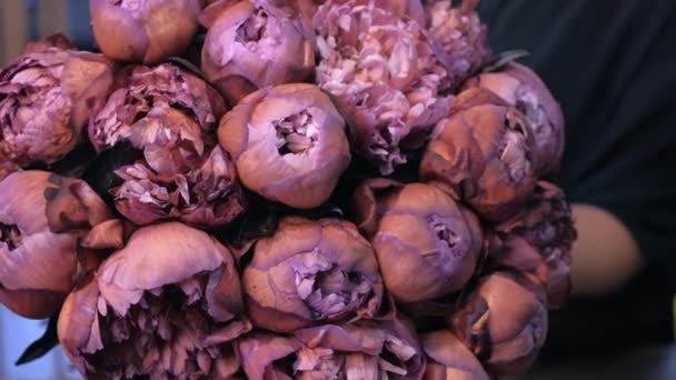 Bloemist houden grote mooie boeket van bruin kastanjebruine kleur pioenrozen in bloemenwinkel. — Stockvideo