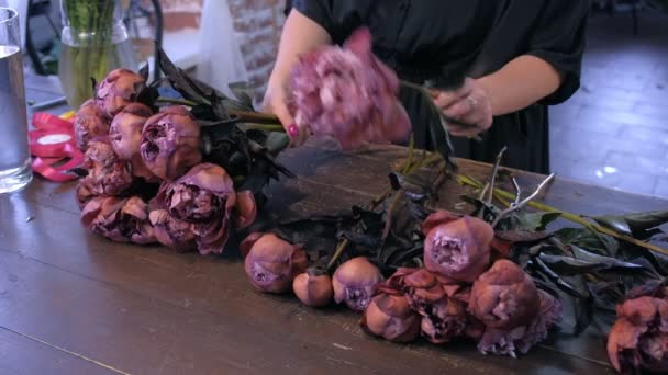 Florista mulher trabalha faz buquê de peônias de cor marrom marrom marrom na loja de flores . — Vídeo de Stock