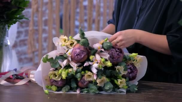 Florista mujer hace gran ramo de flores y lazos tallos de cinta en floristería . — Vídeos de Stock