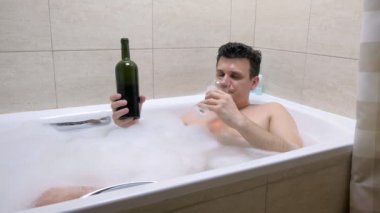 Sarhoş adam banyoda yatıyor ve yüzünde şarap döküldü.