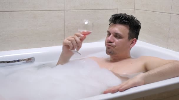 Drunk man lies in bath and spill wine on his face. — Stock Video