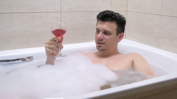 Hombre 30s es relajarse en el baño y beber vino tinto . — Vídeos de Stock