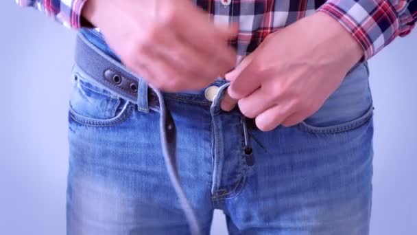 男はほとんどジーンズのベルトをバックルし、胃を引っ張り、手をクローズアップ. — ストック動画