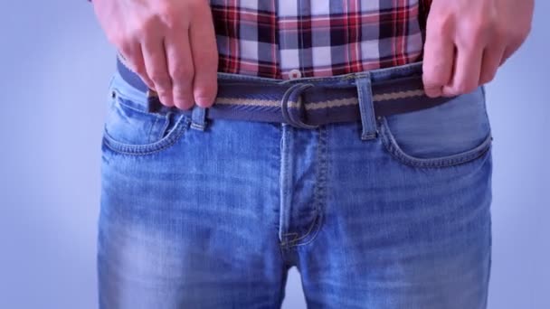 Man drar upp jeans med ett bälte, midja närbild. — Stockvideo
