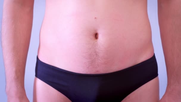 El hombre adelgazante en pantalones muestra el resultado. Restos de exceso de grasa en el estómago . — Vídeos de Stock