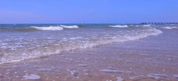 Güneşli bir günde uzun büyük dalgalar ve mesafe oin kum plaj iskele ile deniz kıyısı. — Stok fotoğraf