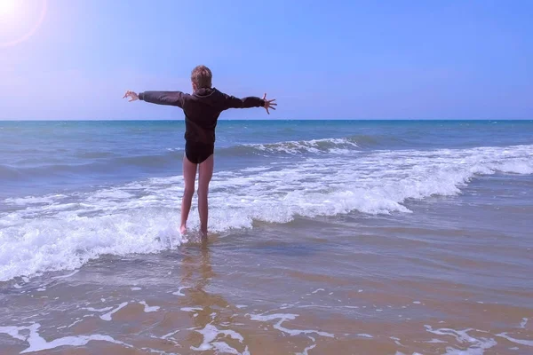 子供の男の子は、休暇に風の晴れた日に海で波の間で再生し、ジャンプ. — ストック写真