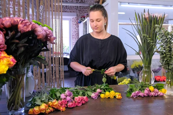 Florista prepara flores para cacho corta rosa espinhos sobre mesa na loja de flores . — Fotografia de Stock