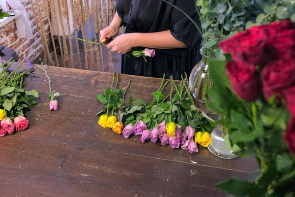 Fiorista donna prepara fiori per bouquet tagliare spine rosa in negozio, primo piano vista . — Foto Stock