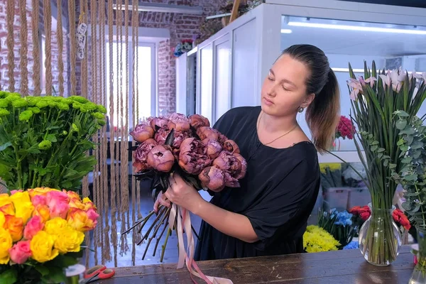 Florista mulher trabalha faz buquê de peônias de cor marrom marrom marrom na loja de flores . — Fotografia de Stock