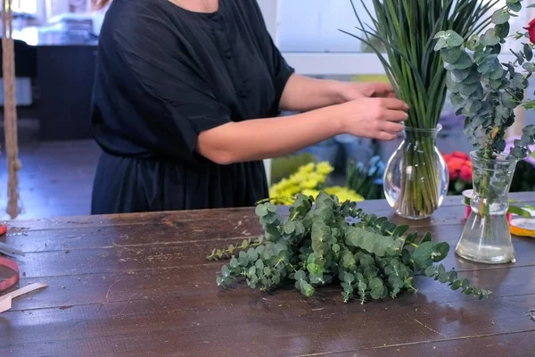 Mujer florista prepara flores de eucalipto e iris para ramo en la tienda en venta . — Foto de Stock