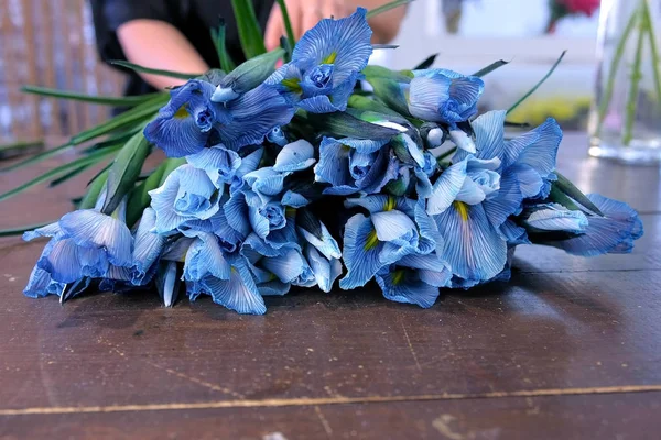 Florista mulher cria buquê de flores de íris azul na mesa para venda na loja . — Fotografia de Stock