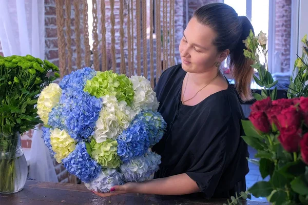 Florista mujer con enorme ramo de flores de hortensias en la tienda de flores . — Foto de Stock