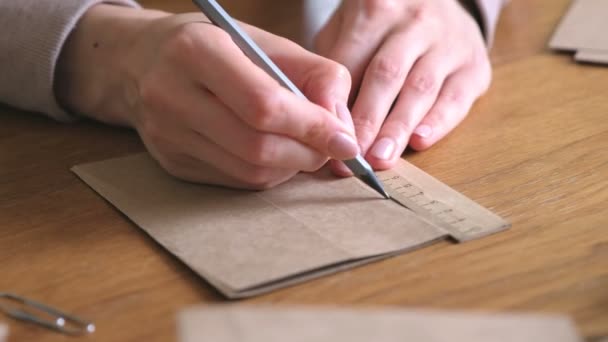 Une femme fabrique des sacs en papier kraft. Les mains en gros plan. Mesures avec une règle et un crayon . — Video