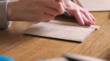 Kadın kraft kağıttan kağıt torba yapıyor. Eller yakın çekim. Cetvel ve kalemile ölçüler.