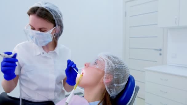 Higienista dentista faz limpeza de dentes ultra-sônicos para jovem na odontologia . — Vídeo de Stock