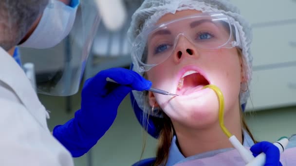 Dentista verter agua en los dientes de la mujer utilizar eyector de saliva durante la limpieza por ultrasonido . — Vídeos de Stock