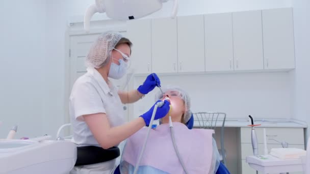 Mondhygiënist schoonmaken en poetsen dames tanden maakt gebruik van boor met borstel. — Stockvideo