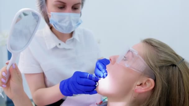 El dentista limpia los dientes de las pacientes con hilo dental en la clínica de estomatología . — Vídeo de stock