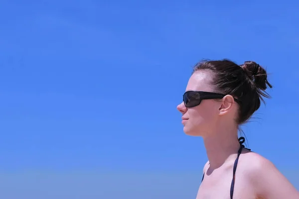 Retrato de mujer joven en gafas de sol sobre fondo azul cielo, vista lateral . — Foto de Stock