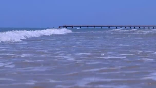 Natural foamy big waves in ocean with wood pier on background in stormy day. — Stock Video