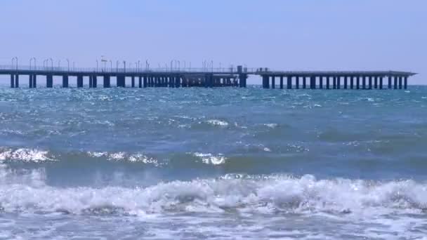 Grote lange pier met straatverlichting, hek en helikopterplatform op zee. — Stockvideo