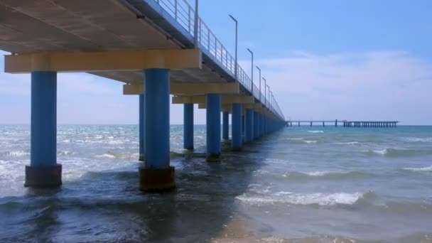 Grote lange pier met straatverlichting, hek en helikopterplatform op zee. — Stockvideo