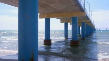 Güneşli bir günde dalgalar ile kumlu plajda okyanus iskelesi altında görünümü.