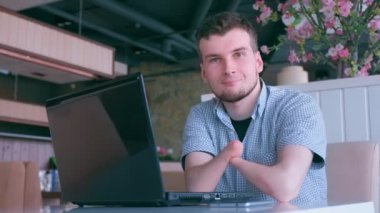 Kafede iki kütük eli amputatlı iyimser engelli adam kameraya bakıyor.