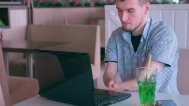 İki tane kütüğü olan engelli adam kafede dizüstü bilgisayarda çalışmayı bitirdi.