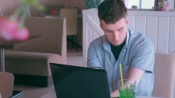 Инвалид с пнем на руках работает в кафе на ноутбуке и разговаривает по мобильному телефону . — стоковое видео