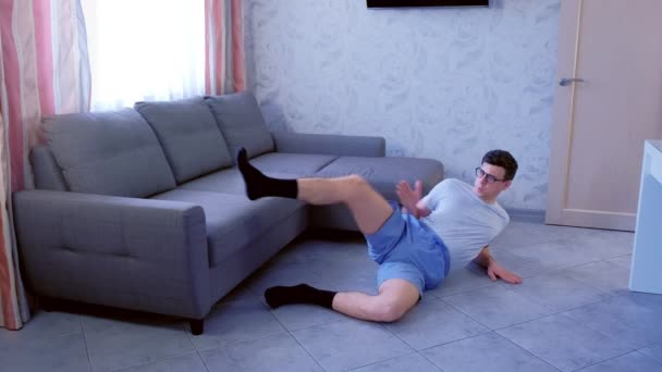 Crazy nerd ember csinál vicces alakításában gyakorlatokat lábak szóló, a padlón otthon. Sport humor koncepció. — Stock videók