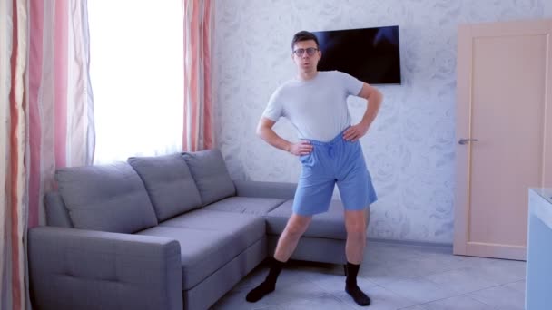 Homem nerd engraçado está fazendo exercícios de fitness rotações pélvis em casa. Conceito de humor esportivo . — Vídeo de Stock