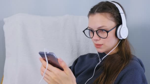 Mujer escucha música en los auriculares en el teléfono inteligente y canta una canción . — Vídeo de stock