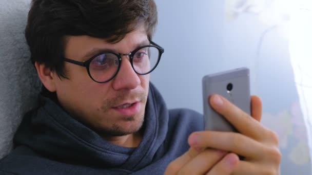 Щасливий молодий чоловік в окулярах розмовляє відео чатом на смартфоні, обличчя крупним планом . — стокове відео