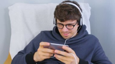Adam gözlük ve kulaklık smartphone içinde bir oyun oynuyor. Oyun sakin ol.
