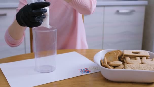 Womans kezek megteszik a cukor édes jegesedés a zsákban díszítő cookie-k és mézeskalács házak. Főzés házi mézeskalács ház. — Stock videók