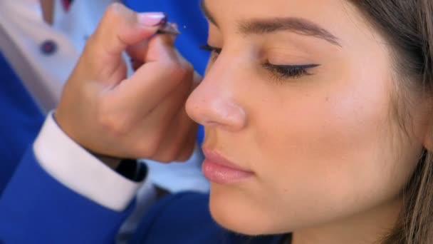 Maquillaje artista pega pestañas artificiales para niña modelo, ojos y cara primer plano . — Vídeos de Stock