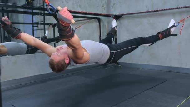 Ejercicios de hacer deportista utiliza entrenador para el estiramiento miofascial en el aire en el gimnasio . — Vídeo de stock