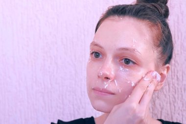 Kadın hindistan cevizi kabuğundan yüzüne taze ev yapımı hindistan cevizi maskesi uyguluyor.