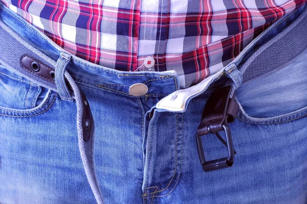 El hombre se desabrochó el cinturón y se desabrochó los pantalones vaqueros con las manos después de cenar fuerte. . —  Fotos de Stock