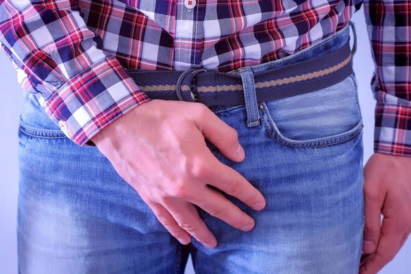 El hombre se cubre en la entrepierna en jeans por las manos . —  Fotos de Stock