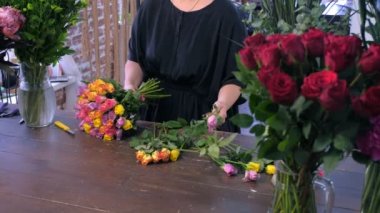 Çiçekçi kadın eserleri dükkanda renkli güllerden buket yapar, eller çekim.