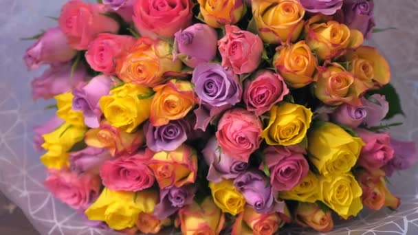 Piękny bukiet kolorowych róż w białym papierze w kwiaciarni, widok zbliżenie. — Wideo stockowe