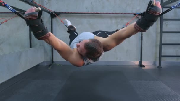 Ejercicios de hacer deportista utiliza entrenador para el estiramiento miofascial en el aire en el gimnasio . — Vídeo de stock