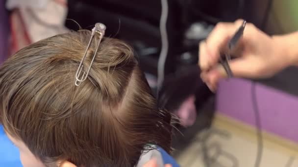 Hairdresser cuts hairs with scissors on boys head. Top view, stylists hands close-up. — Stock Video