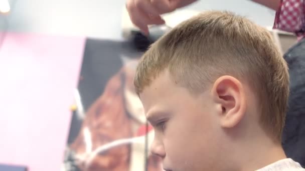 理发师用剪刀在男孩头上剪下，面对特写的侧视图。造型师手. — 图库视频影像