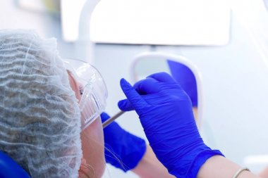 Kadın hasta önleyici muayene sırasında diş hekimliği koltuğunda aynaya bakıyor.