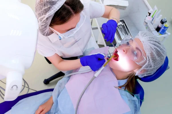Dentist pour water on woman teeth use saliva ejector during ultrasound cleaning.